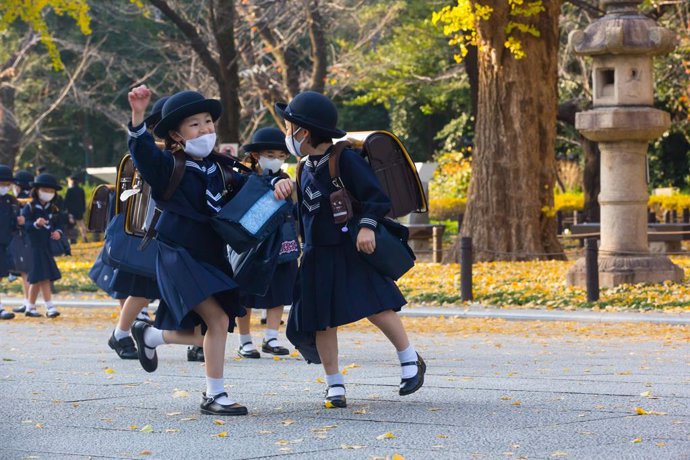 Archivo - November 26, 2020, Tokyo, Japan: Japanese elementary school students dressed in traditional uniforms while wearing face masks walk back home after their lessons.