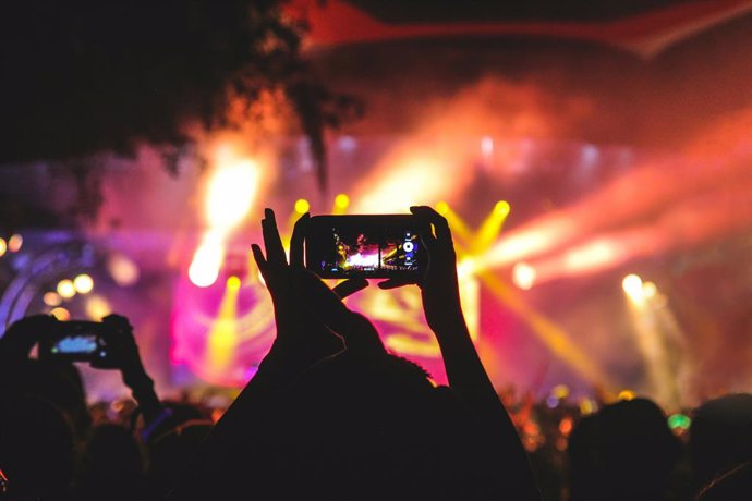 Recurso de persona grabando un concierto en un festival