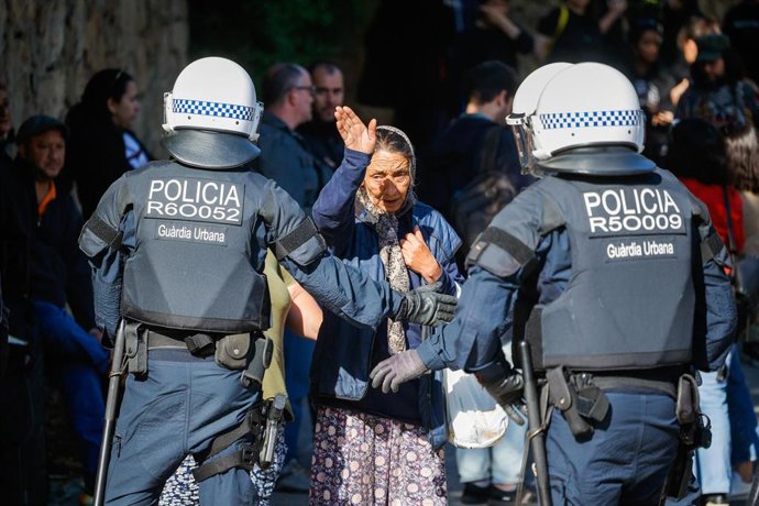 Agentes de Guardia Urbana delante de una mujer durante un dispositivo para completar el desalojo del asentamiento de chabolas del barrio barcelonés de Vallcarca, a 8 de mayo de 2025, en Barcelona, Catalunya (España)