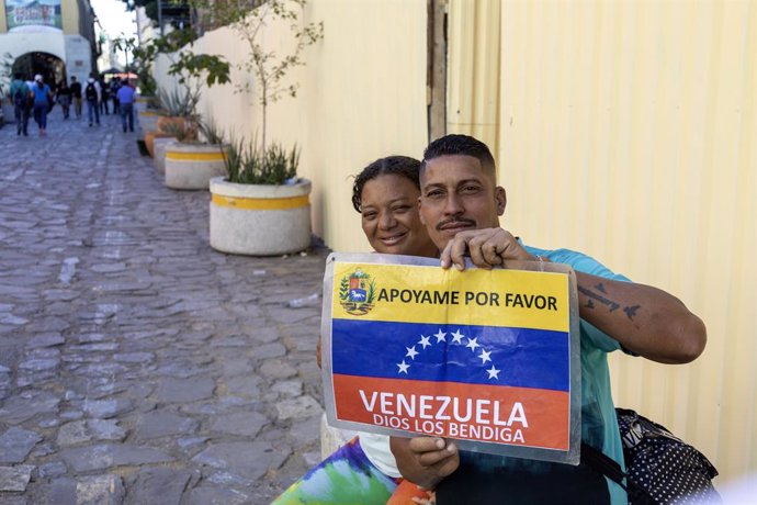 Archivo - February 20, 2024, Oaxaca, Oaxaca, USA: Oaxaca, Mexico - A man and a woman trying to make their way from Venezuela to the United States hold a sign asking for help.