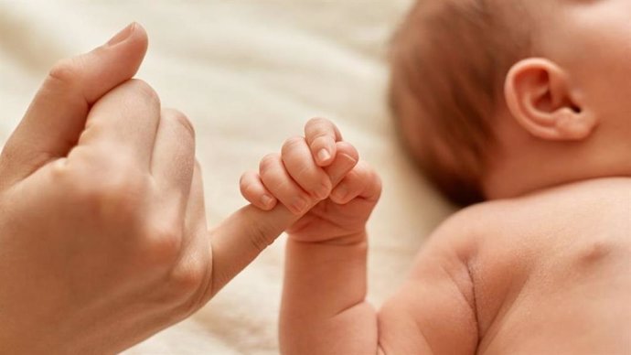 Un bebé agarra el dedo de su madre.
