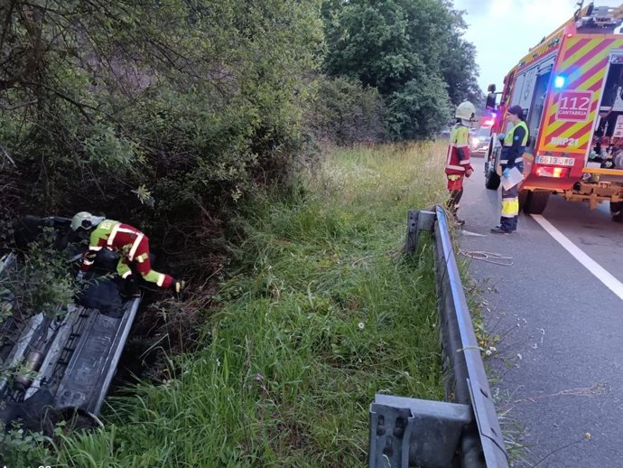 Bomberos ayudan a un ocupante a salir de un vehículo volcado.