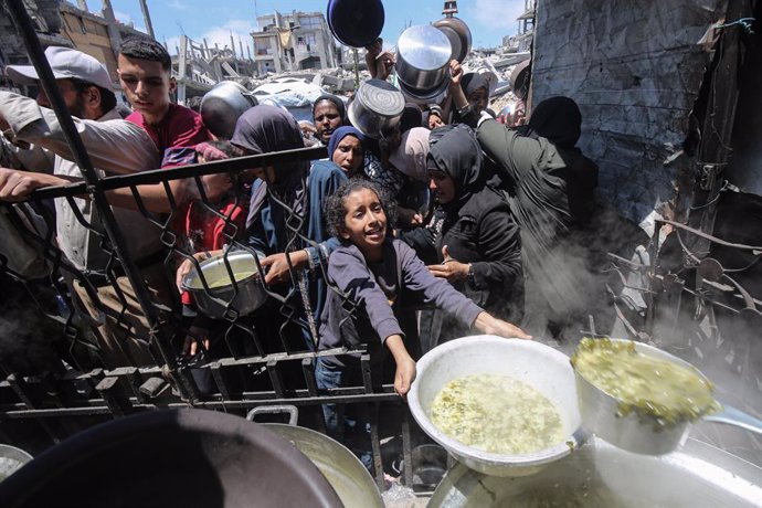 May 8, 2025, Gaza City, Gaza Strip, Palestinian Territory: Palestinians wait in long queues to receive pots of food distributed by charitable organizations, in Beit Lahia, northern Gaza Strip. Food crisis in the Gaza Strip deepens day by day due to the cl