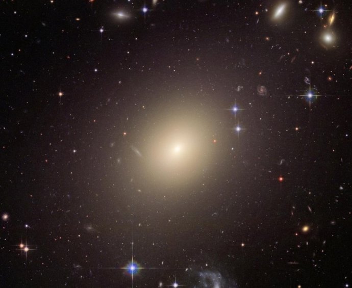 La enorme galaxia elíptica ESO 325-G004 brilló 10.000 veces más cuando se formó que hoy. Este tipo de galaxias iluminó brevemente todo el universo y contribuyó a la radiación de fondo que podemos medir hoy.