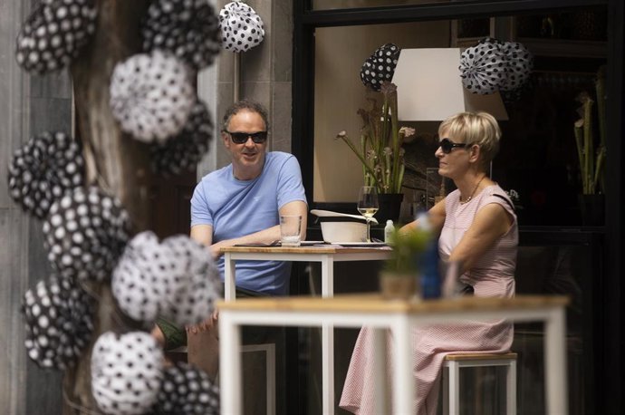 Archivo - Dos personas en un bar decorado con los farolillos tradicionales de la Feria de Abril, en foto de archivo.