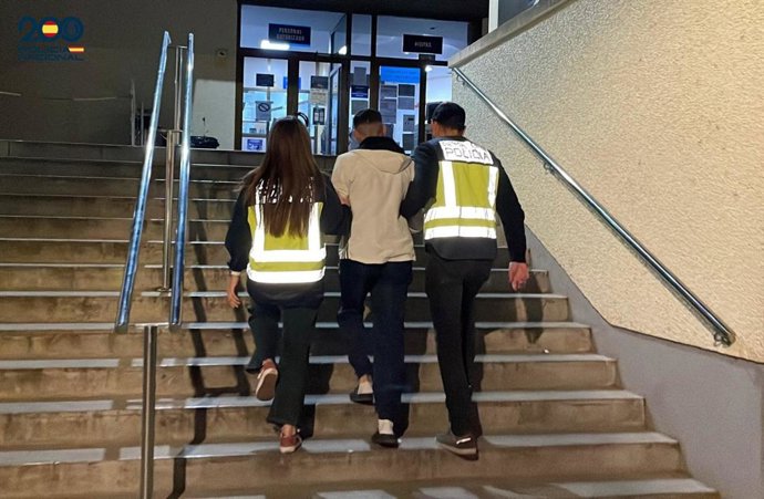 El fugitivo, de espaldas y junto a dos agentes de la Policía Nacional, entrando en dependencias policiales.