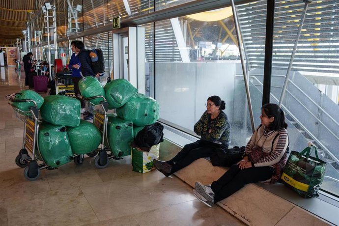 Varias personas sentadas en la terminal T4 del aeropuerto Adolfo Suárez-Madrid Barajas