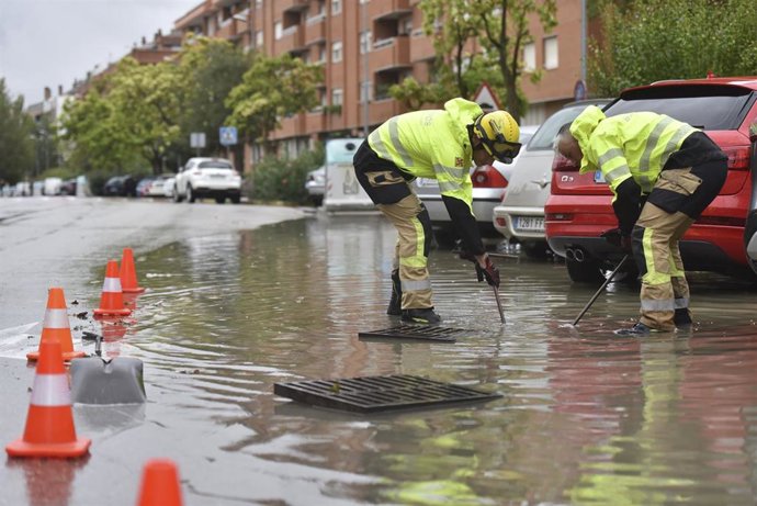 Archivo - Dos hombres desatascan una alcantarilla.