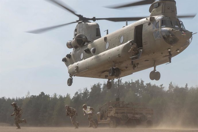 14 de abril de 2025 - Hohenfels Joint Multinational Re, Bayern, Alemanha - Aviadores dos EUA designados para a 435th Air Ground Operations Wing fogem de um helicóptero CH-47 Chinook carregando dois veículos táticos leves todo-terreno durante o exercício A