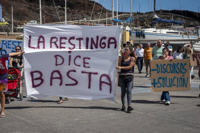 Archivo - Varias personas durante una manifestación en contra de que instalaciones de acogida de personas migrantes en el puerto de La Restinga