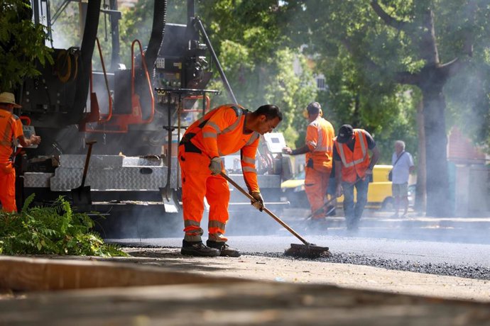 Archivo - Operarios municipales se afanan en el asfaltado de la calle Victoria Domínguez, en el Polígono Sur, en foto de archivo.
