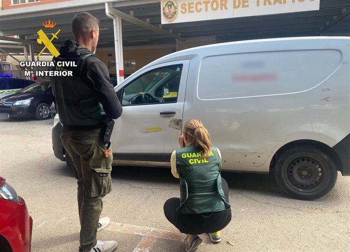 Dos agentes de la Guardia Civil junto a la furgoneta implicada en el siniestro