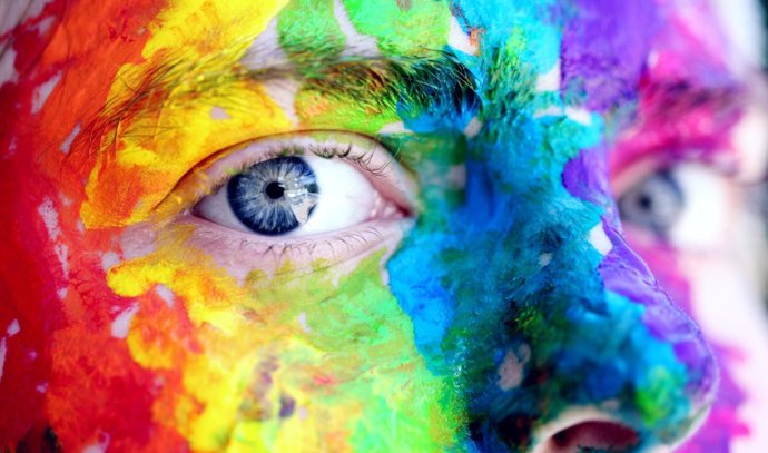 Una cara pintada con los colores de la bandera LGTBI.