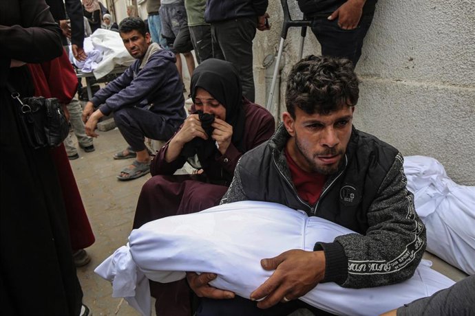 Palestinos junto a un cadáver a causa de un bombardeo ejecutado por el Ejército de Israel contra una escuela convertida en refugio para desplazados en la ciudad de Gaza, en el norte de la Franja de Gaza (archivo)