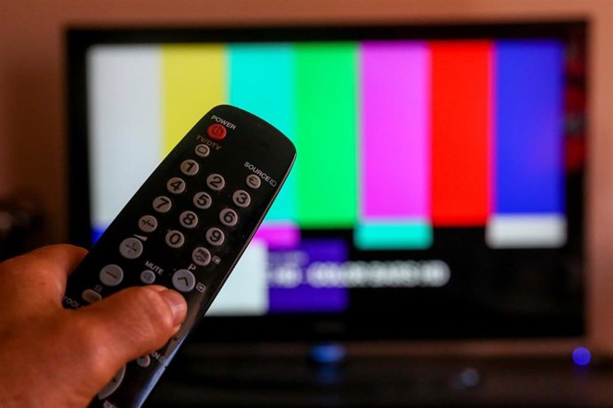 Archivo - Una persona utiliza su mando de la televisión para buscar canales.