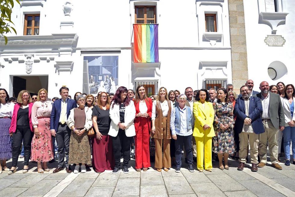 Foto de familia con la bandera arcoiris tras el acto institucional en la Asamblea por el Día contra la LGTBIFobia.
