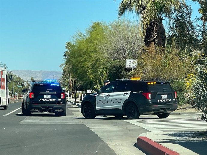 Archivo - Arquivo - 10 de março de 2025, Palm Springs, Califórnia, EUA: Dois veículos do Departamento de Polícia de Palm Springs estão posicionados em um cruzamento, bloqueando parte da estrada. Um SUV da polícia está com suas luzes de emergência azuis pi