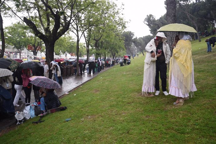 Varias personas se protegen de la lluvia en la pradera de San Isidro, a 15 de mayo de 2025, en Madrid (España). La ciudad de Madrid celebra la festividad de su patrón, San Isidro, con unas fiestas que comprenden este año más de 200 eventos previstos con p
