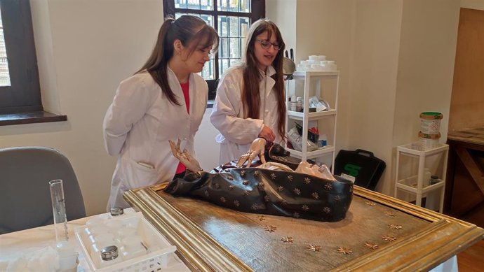 Dos de las estudiantes en prácticas en el Museo de la Iglesia de Asturias, junto al busto 'Mater Dolorosa' que han contribuido a restaurar.