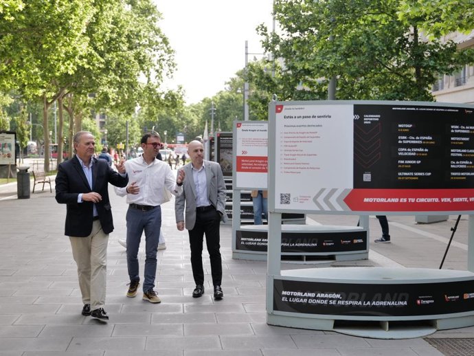 El gerente de MotorLand Aragón, Jorge Panadés, el gerente de Zaragoza Turismo, José Francisco García, y el director general de Turismo y Hostelería, Jorge Moncada, inauguran una exposición dedicada al circuito de velocidad en el paseo Gran Vía de Zaragoza