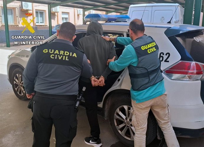 Dos agentes custodian a uno de los arrestados