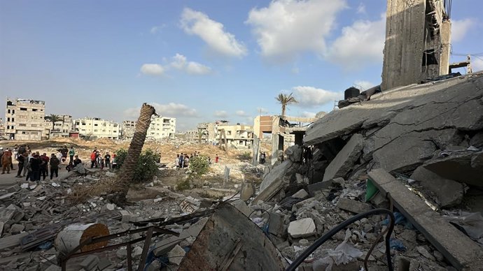Palestinos em meio aos destroços de edifícios destruídos na ofensiva militar de Israel em Khan Younis, no sul da Faixa de Gaza.