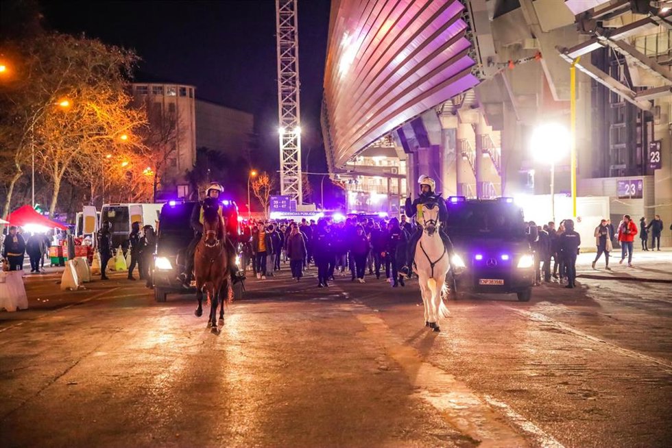Archivo - Agentes de la Policía Nacional escoltan a aficionados en las inmediaciones del estadio Santiago Bernabéu 