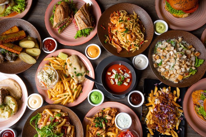 Mesa con comida, sopa, salsa, fristos, pasta, hamburguesa, patatas