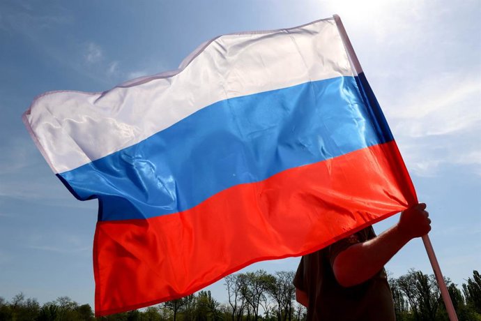 RÚSSIA, MELITOPOL - 6 DE MAIO DE 2025: Um representante das autoridades da região de Zaporozhye e das agências de aplicação da lei agita a bandeira russa durante o evento ZaBeg [Run] 1418 realizado no Estádio Spartak para marcar o 80º aniversário da vitór