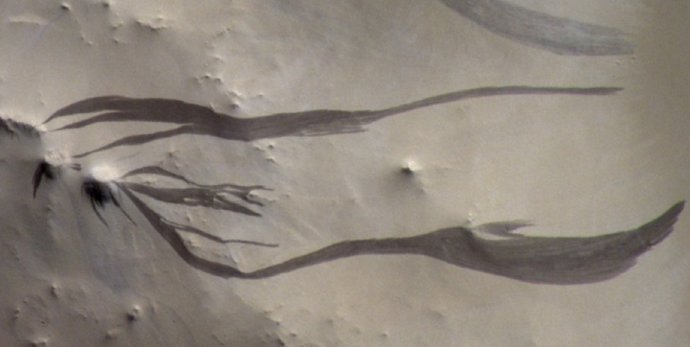A câmera CaSSIS a bordo do ExoMars Trace Gas Orbiter da ESA captura faixas escuras, semelhantes a dedos, na superfície empoeirada de Marte em Arabia Terra.