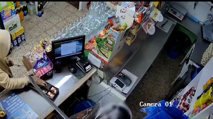 Uno de los atracadores comete un robo en una tienda de alimentación de Utrera.