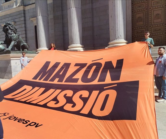 Jóvenes de Compromís despliegan una pancarta en la Puerta del Congreso exigiendo la dimisión de Mazón
