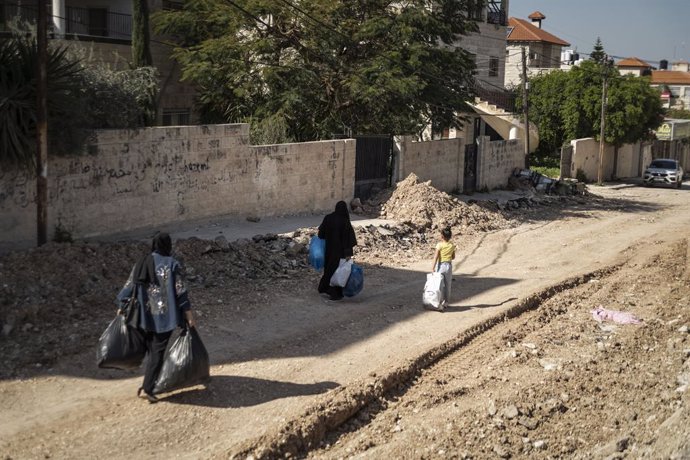 Archivo - 15 March 2025, Palestinian Territories, Jenin: people walk among the rubble holding bags in he Jenin refugee camp which has been under the Isaeli Iron Wall military operation since January 21, 2025. Around 50000 resident have been evicted and fo