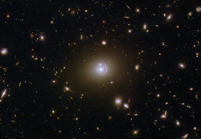 Esta imagem do Telescópio Espacial Hubble da NASA/ESA mostra a galáxia remota HerS 020941.1+001557, que aparece como um arco vermelho envolvendo parcialmente uma galáxia elíptica em primeiro plano.