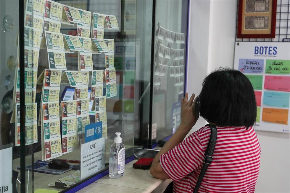 Archivo - Una mujer compra lotería en una Administración 