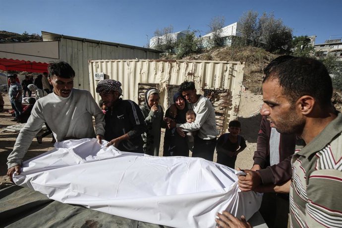 Palestinos junto a un cadáver tras un ataque del Ejército de Israel contra la Franja de Gaza en medio de la ofensiva lanzada contra el enclave tras los ataques del 7 de octubre de 2023 (archivo)