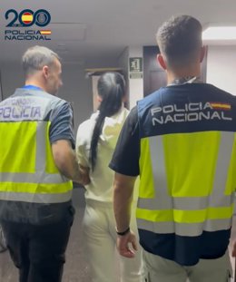 Una de las mujeres arrestadas, conducida por agentes.