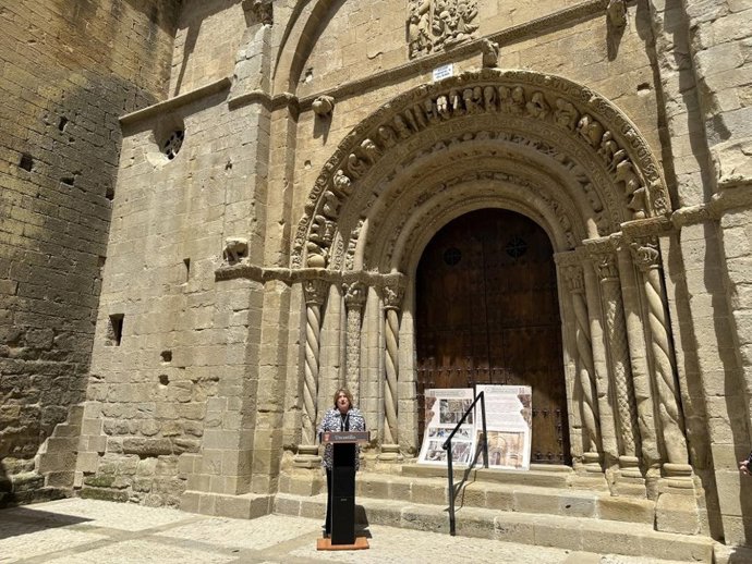 La consejera de Educación, Cultura y Deporte, Tomasa Hernández, frente a la portada sur de la Iglesia Parroquial de Santa María la Mayor de la localidad zaragozana de Uncastillo, Zaragoza