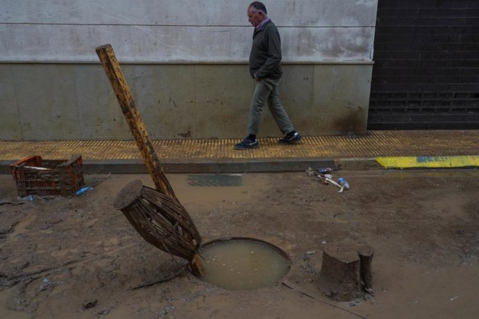 Archivo - Una persona pasea por la calle llena de barro, a 13 de noviembre de 2024, en Catarroja,  Valencia