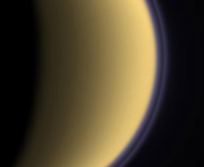 Neblina púrpura alrededor de Titán: Imagen en falso color de Titán captada en 2004 por la sonda Cassini. La neblina púrpura muestra la densa atmósfera que envuelve el cuerpo dorado de la luna.