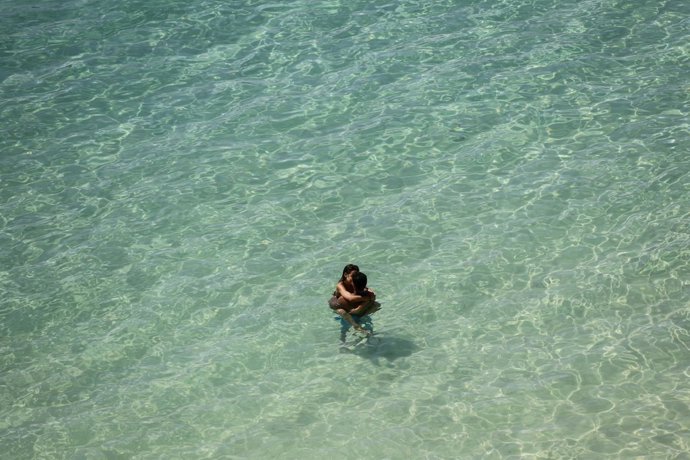 Archivo - A young couple kisses while bathing in the sea at Portals Nous beach. 