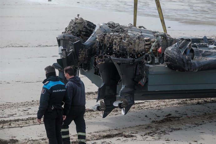 Archivo - Un policía junto a la planeadora varada en la playa de Nemiña, en Muxía. Archivo.