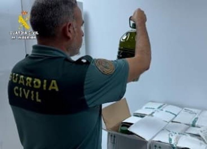 Agente de guardia civil con una botella de aceite intervenida