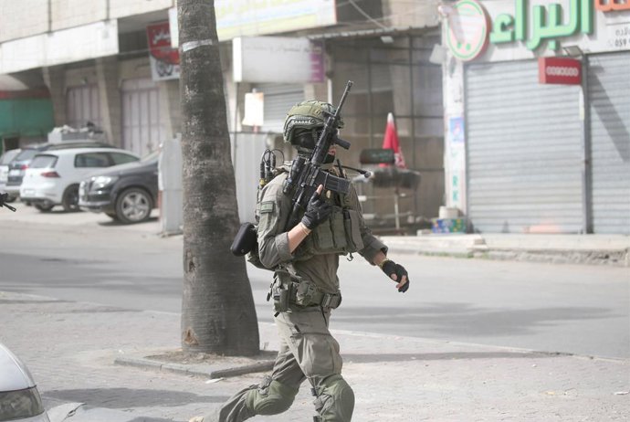 18 de maio de 2025, Territórios Palestinos, Nablus: Um soldado israelense corre pela rua para assumir uma posição durante uma operação militar na aldeia de Balata. Forças israelenses invadem uma casa e prendem um palestino procurado pela Autoridade Palest