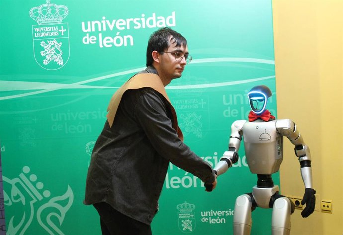 Uno de los graduados saluda al robot humanoide Unitree G1, la última incorporación del Grupo de Robótica de la Universidad de León
