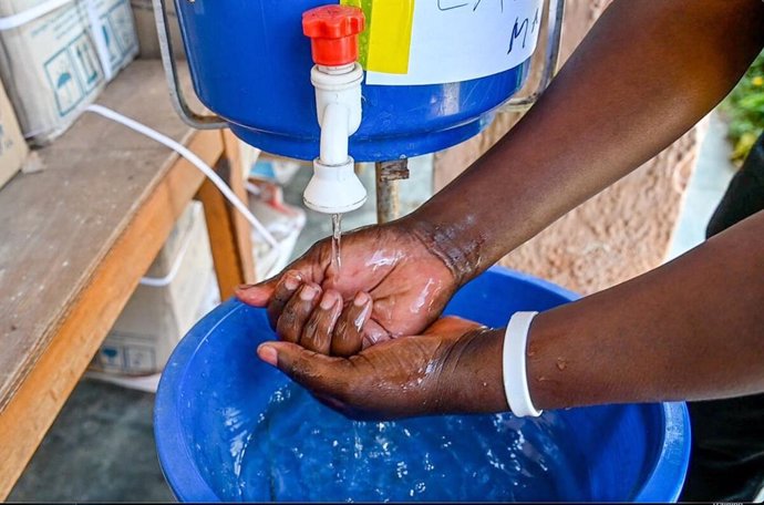 Una persona se lava las manos en un dispensador con una solución clorada al 0.05%, instalada en una comunidad de RDC para fomentar la higiene de manos y prevenir el cólera.