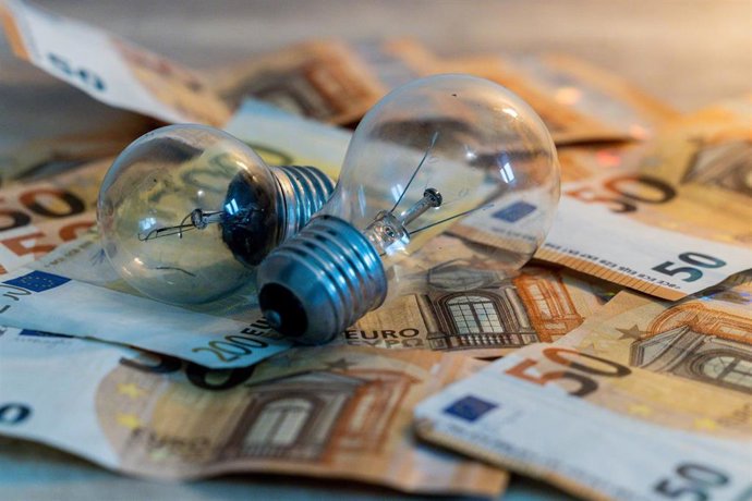 Archivo - Dos bombillas sobre billetes.