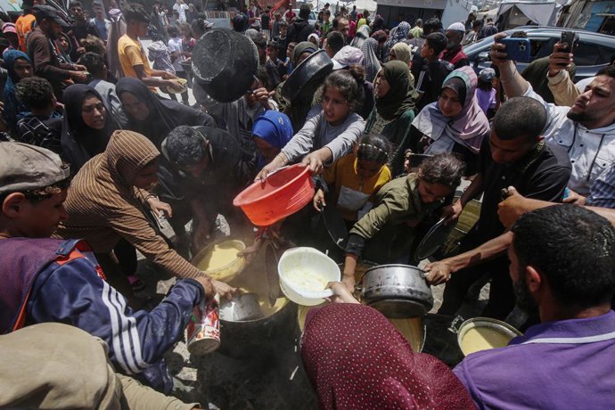 22 de maio de 2025, Cidade de Gaza, Faixa de Gaza, Território Palestino: Palestinos fazem fila para receber uma refeição quente em um ponto de distribuição de alimentos no bairro de Al-Rimal, na Cidade de Gaza, no centro da Faixa de Gaza, em 22 de maio de