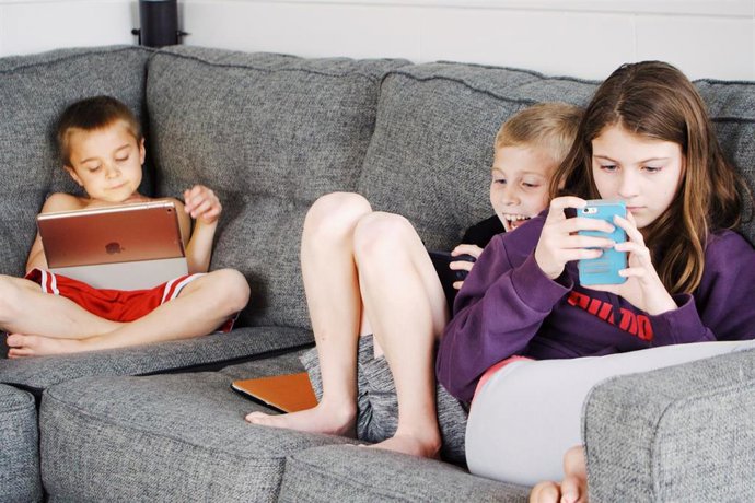 Archivo - Niños utilizando dispositivos móviles.