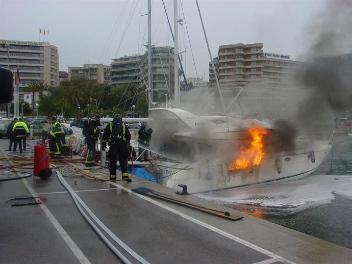 Bomberos tratan de extinguir un incendio en una embarcación en el puerto de Palma.